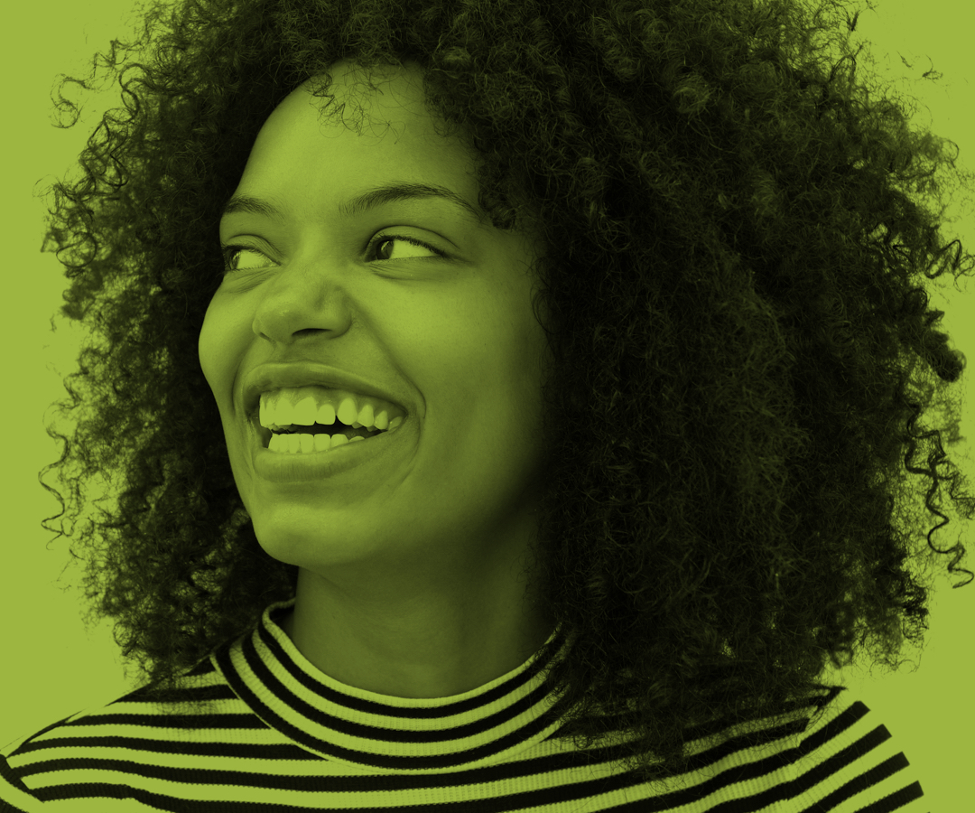 Woman with curly hair smiling widely and looking to the right.